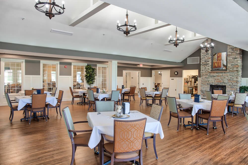 Spacious dining area with neatly arranged tables and elegant chandeliers.