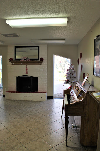 A cozy living room featuring a piano, a fireplace adorned with decorations, and an inviting entrance.