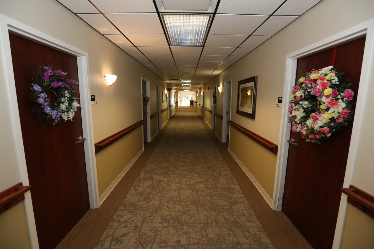A long, carpeted hallway with multiple doors and floral decorations.