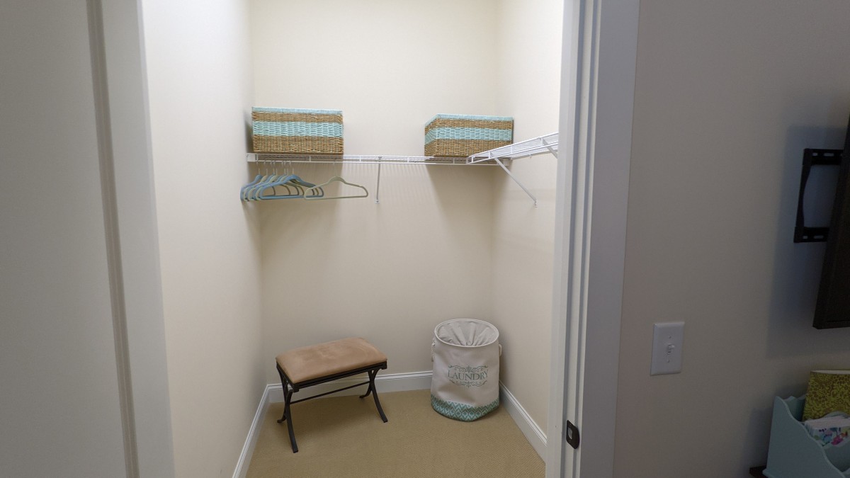 An empty closet with shelves, hangers, and a laundry basket.