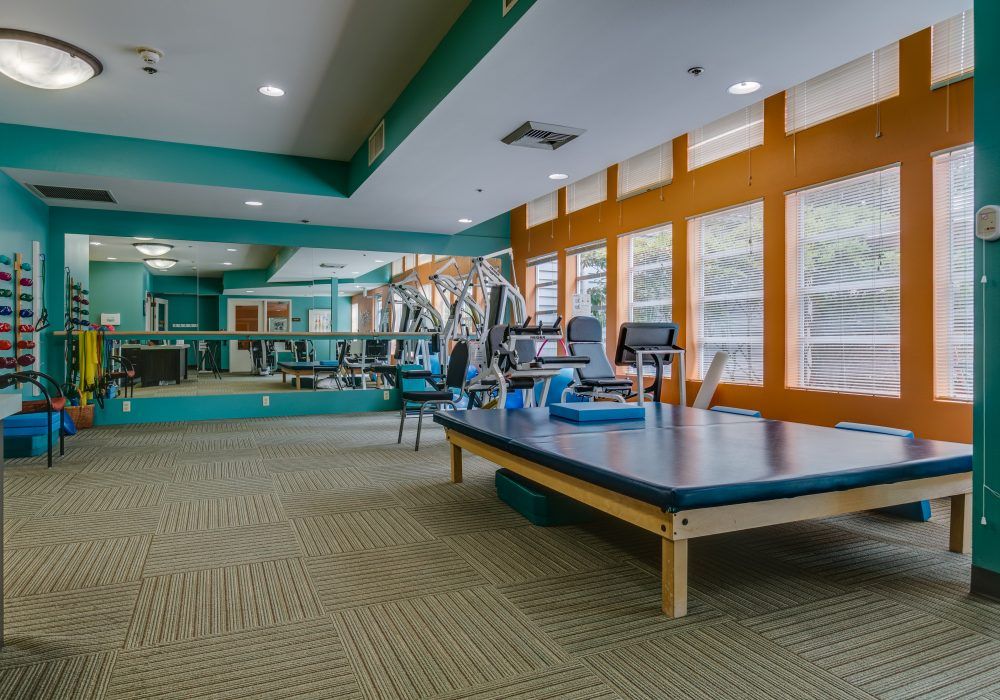 A well-lit gym featuring various exercise equipment and large mirrors.