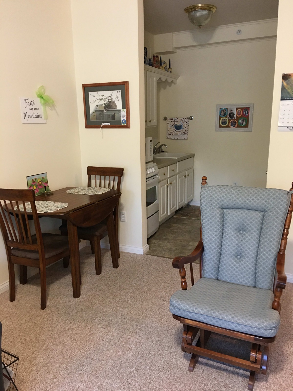 A cozy dining area with a small table, chairs, and an armchair near a compact kitchen.