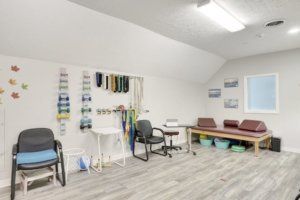 A well-lit therapy room equipped with chairs, desks, and various medical supplies.