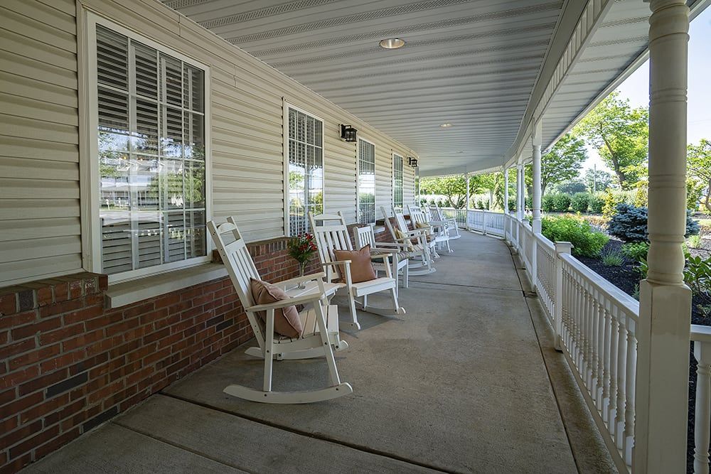 A serene porch with white rocking chairs lined up along a covered patio.