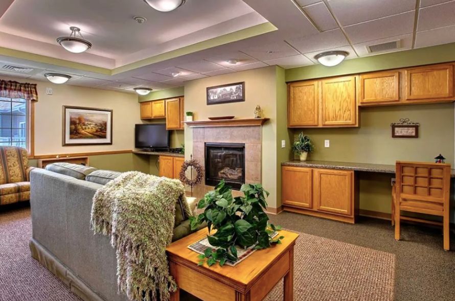A cozy living room featuring a fireplace, television, and wooden cabinetry against green walls.