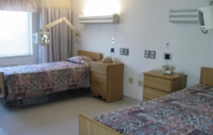 A room featuring twin beds with patterned bedspreads, dressers, and curtains.