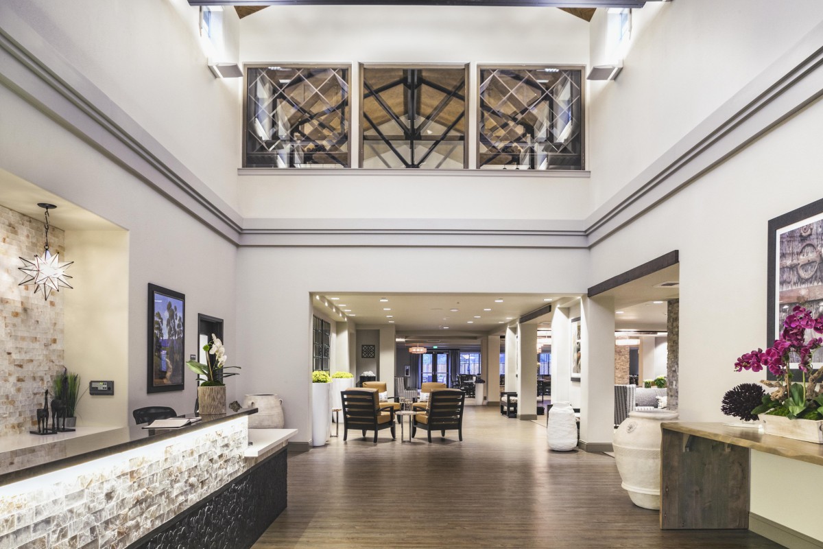 A modern hotel lobby with a reception desk and seating area.