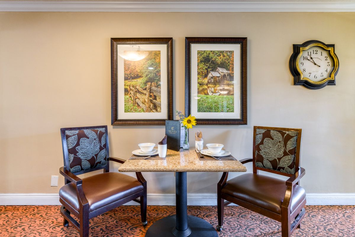 A cozy dining setup with two chairs, a table, and decorative artwork on the wall.