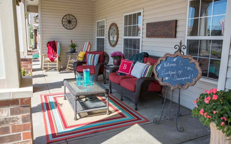 A cozy patio setup with colorful cushions, a rug, and outdoor decor for relaxing.