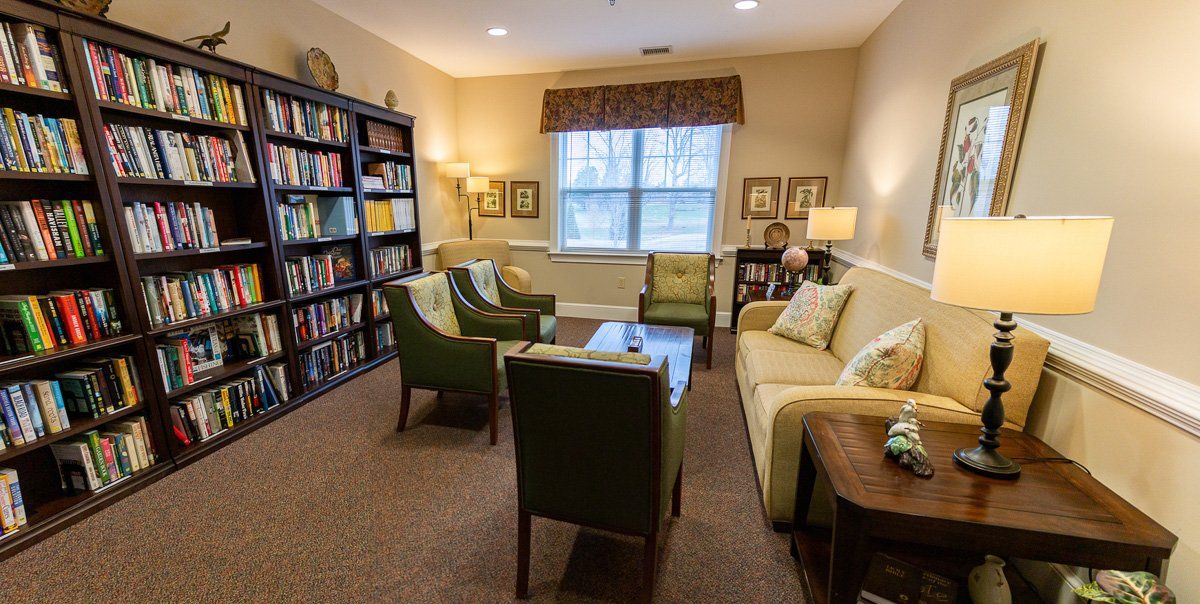 A cozy living room with comfortable seating, a bookshelf filled with books, and warm lighting.