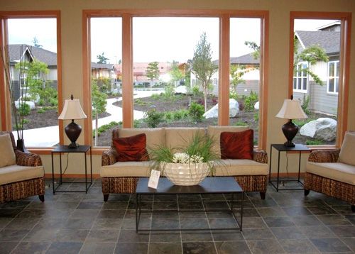 A cozy living room with a sofa, coffee table, and large windows providing an outdoor view.