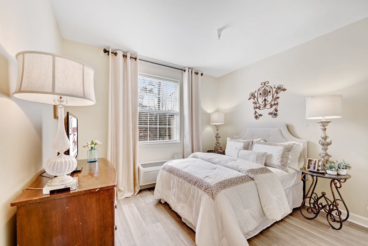 A cozy bedroom with modern decor, featuring a large window and elegant wooden furniture.