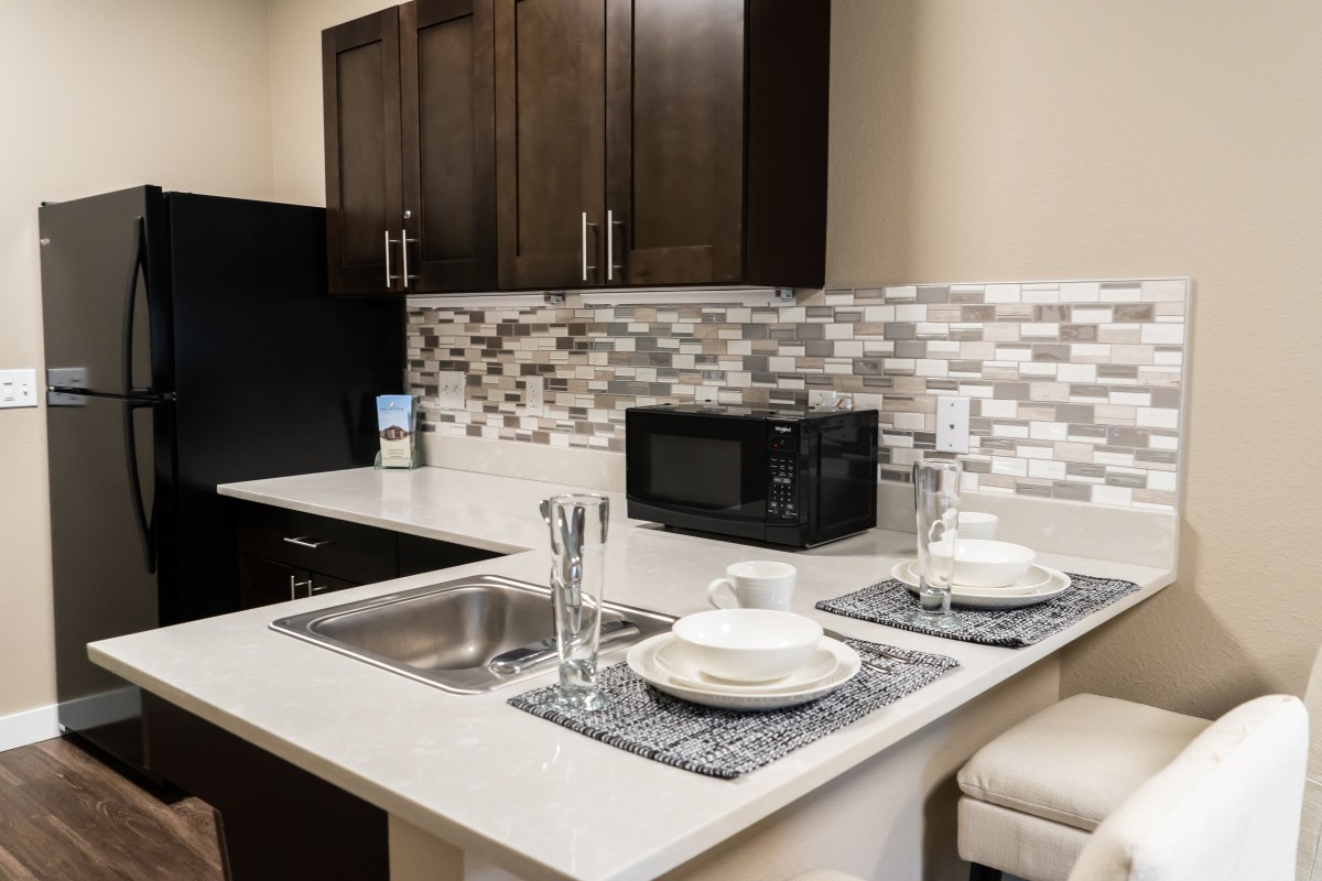A modern kitchen with a stylish countertop featuring a microwave, sink, and dining set.