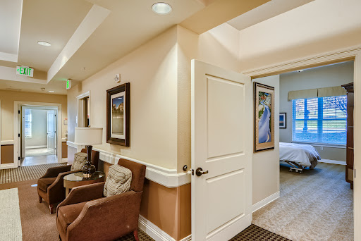 A cozy living room area leading to a private space, featuring comfortable chairs and wall art.