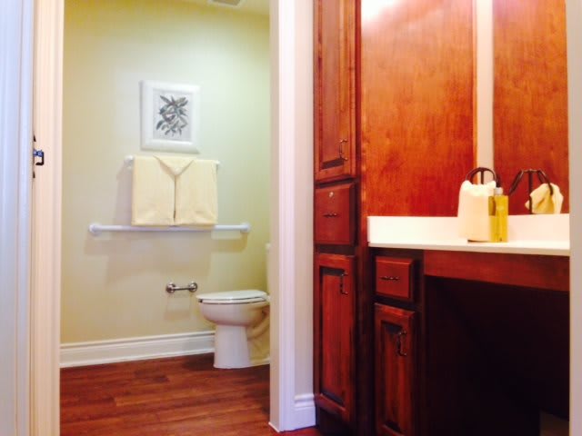 A clean and tidy bathroom with wooden cabinets and flooring.