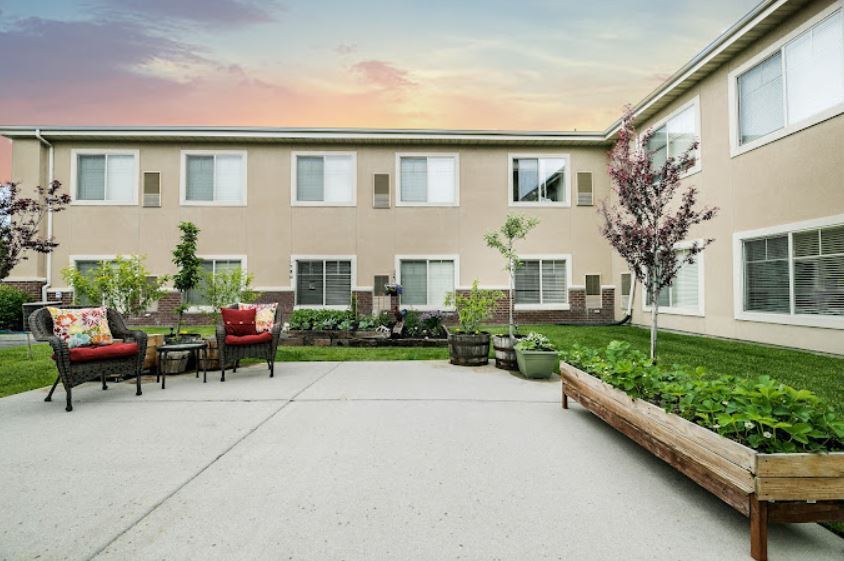 A peaceful courtyard with comfortable outdoor seating and lush landscaping at sunset.