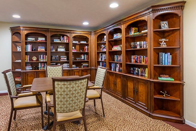 A cozy library with wooden bookshelves, a table, and chairs.