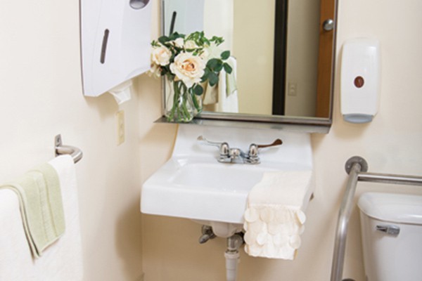 A bathroom sink with a mirror, decorated with a vase of flowers and a neatly folded towel.