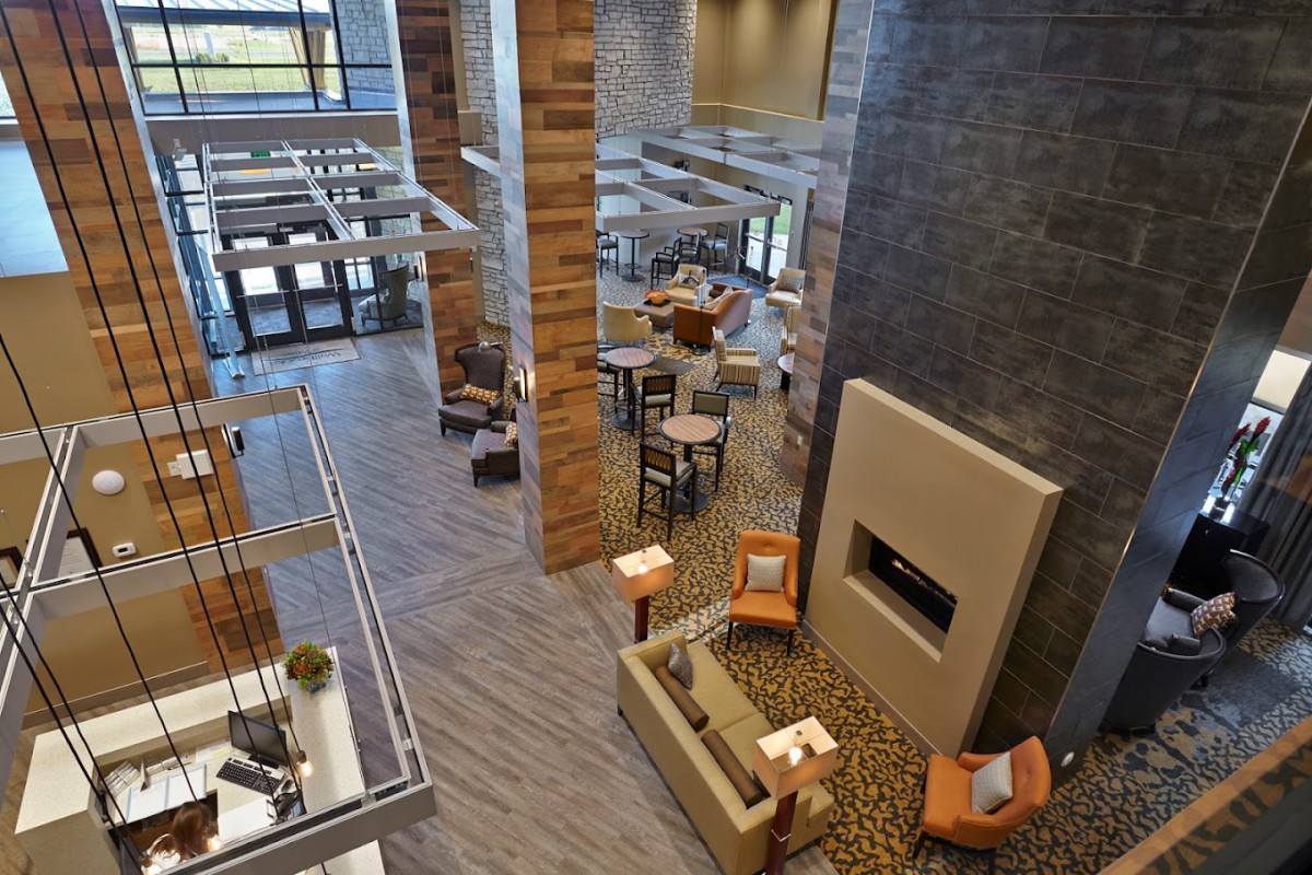 A modern lobby with a cozy seating area and fireplace, featuring wood accents and contemporary furniture.