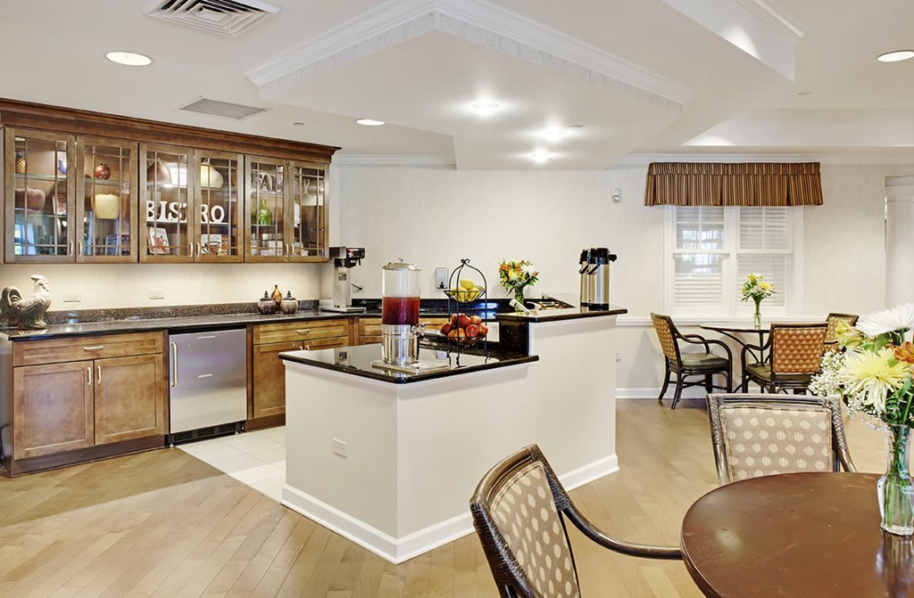 A modern kitchen interior with an island counter and seating area, featuring wood flooring and bright lighting.