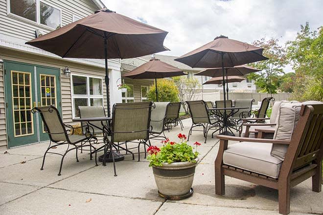 A cozy outdoor patio area with tables, chairs, and umbrellas, complemented by a potted flower arrangement.