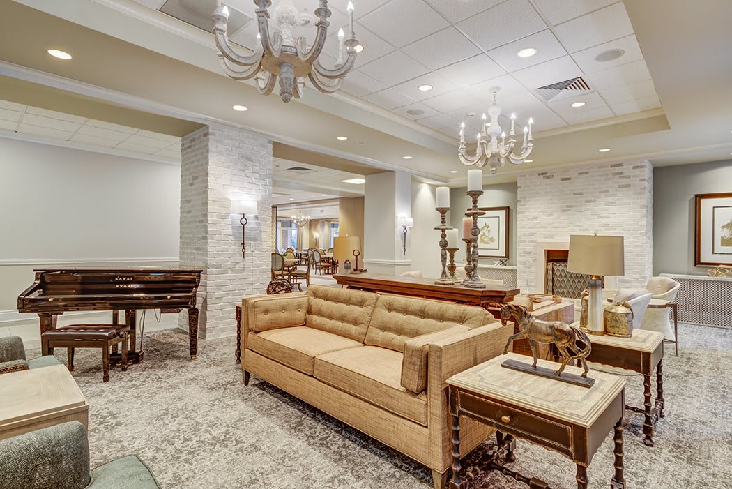 A spacious and elegantly designed living room featuring a comfortable couch, ornate chandeliers, and tasteful furnishings.
