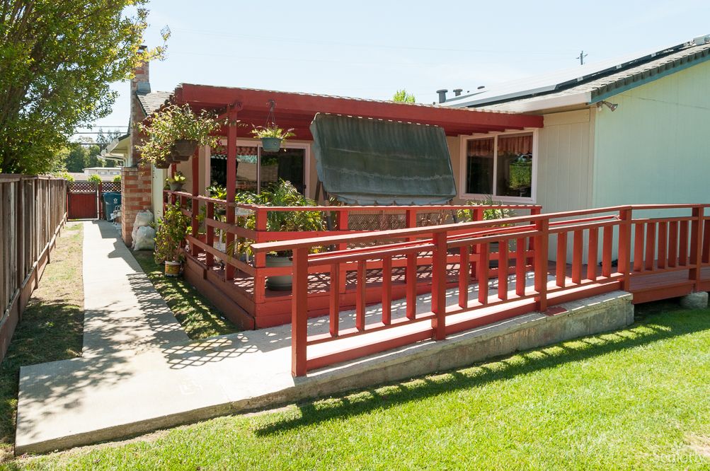A house with a red porch and ramp on a sunny day.