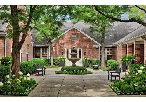 A serene courtyard featuring a beautiful fountain surrounded by well-maintained landscaping and outdoor seating.