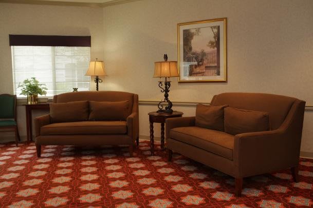 A cozy living room with two brown sofas, decorative lamps, and a patterned carpet.