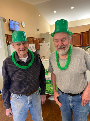 Two cheerful men celebrating St. Patrick's Day with green hats and leis.
