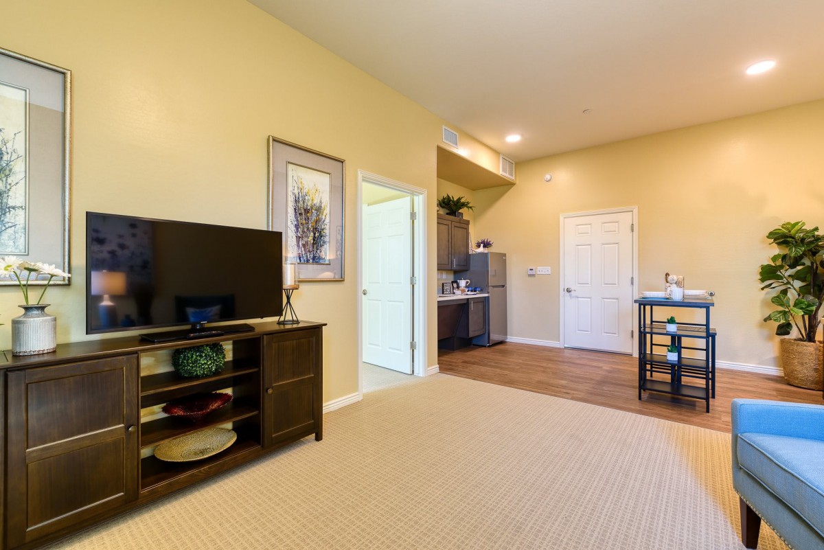 A cozy living room area with a television and a view into the kitchen.