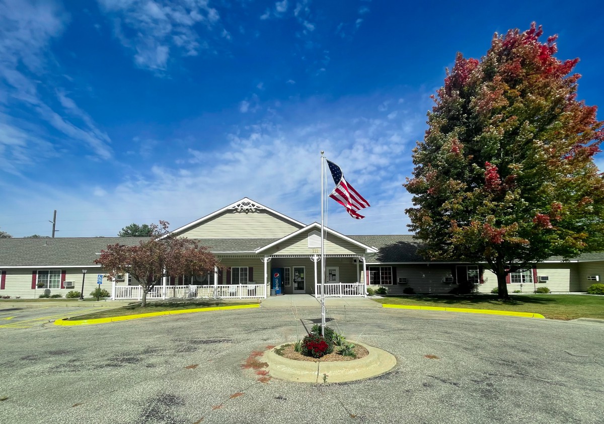A building with a flagpole and trees under a blue sky.