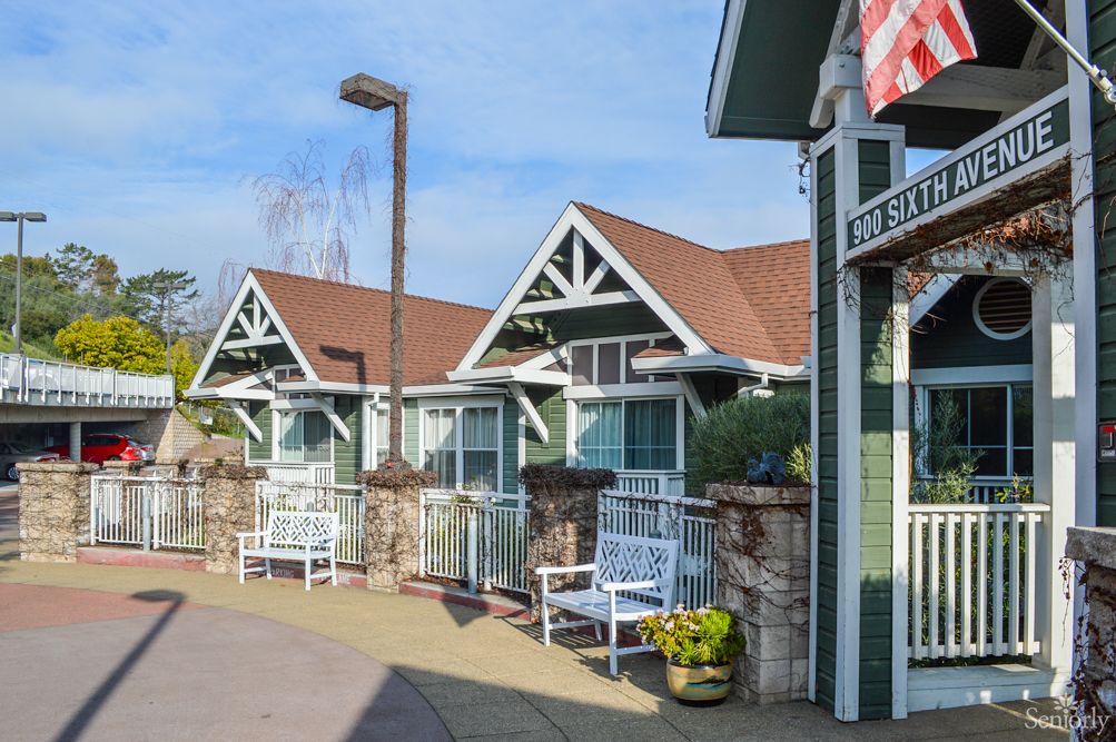 Charming cottages with benches and flowerpots lining a sunny pathway.