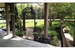 A charming garden with an archway leading to a pathway surrounded by lush greenery.