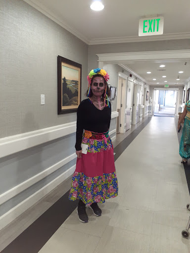 A woman dressed in a vibrant costume stands in a hallway, ready to celebrate.