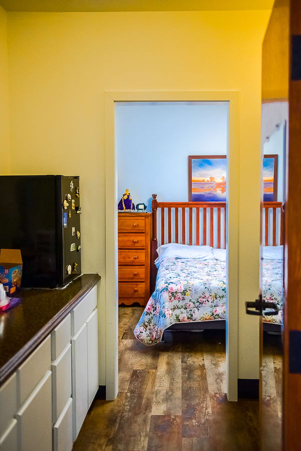 A cozy bedroom with a bed and wooden furniture, viewed from an adjacent room.