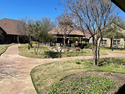 A serene garden setting featuring a winding pathway, trees, and a cozy gazebo under a clear blue sky.