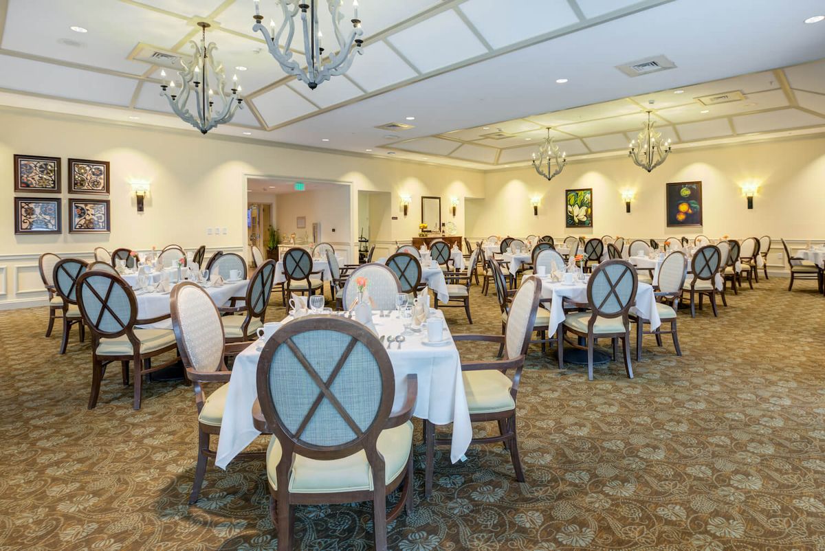 An elegant and empty dining room with neatly arranged tables and chairs.