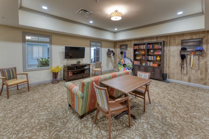 A cozy living room with a television, bookshelf, and seating area.