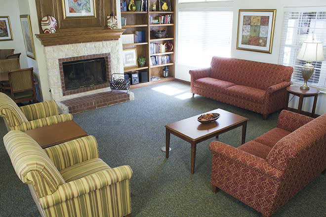 A cozy living room featuring a fireplace, sofas, chairs, a coffee table, and bookshelves.