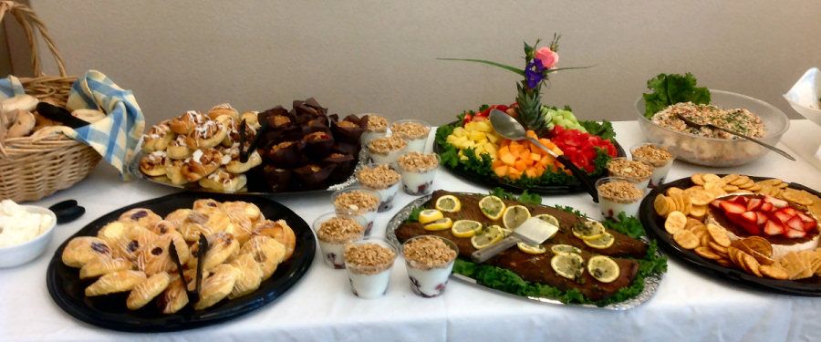 A buffet table featuring a variety of desserts including muffins, yogurt parfaits, and a colorful fruit platter.
