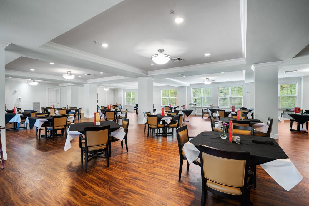 A spacious dining area with neatly arranged tables and chairs, featuring large windows and elegant lighting.