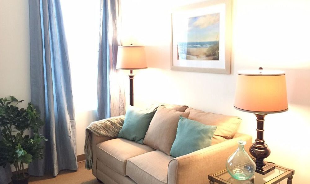 A cozy living room with a beige sofa, blue cushions, and ambient lighting.