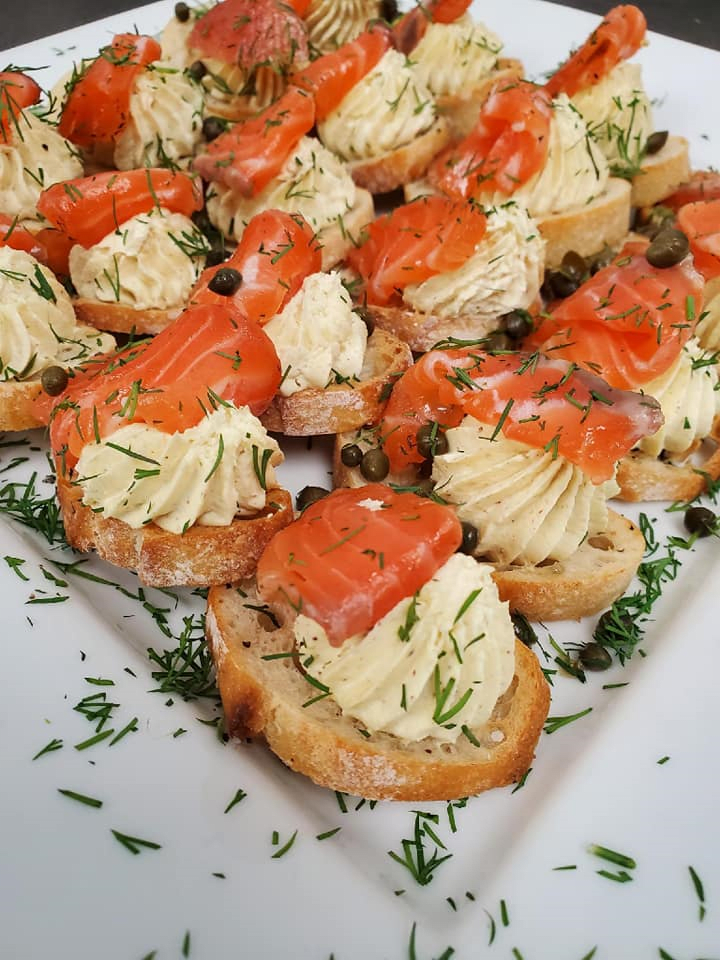 Delicious smoked salmon and cream cheese appetizers garnished with dill and capers on sliced baguette.