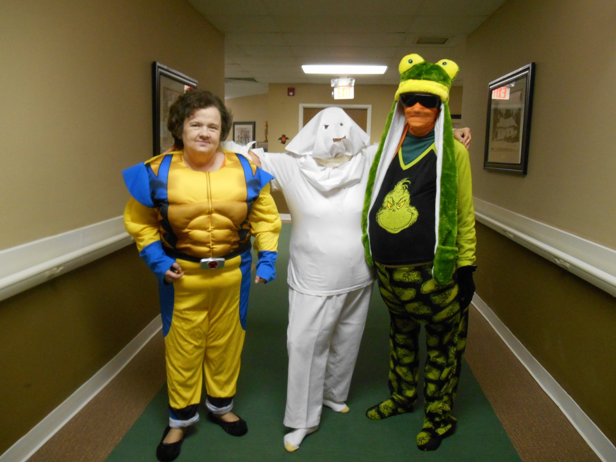 Three people in playful costumes pose together in a hallway.