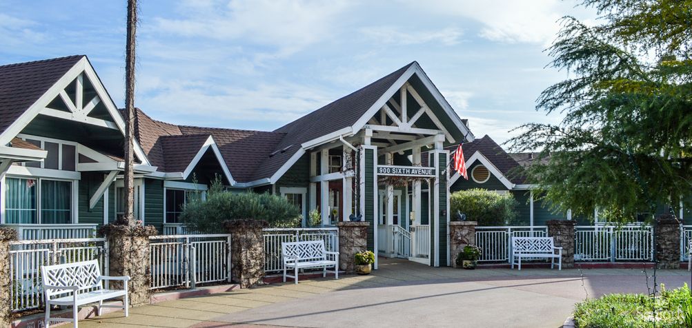 A quaint building with a pitched roof and a welcoming entrance, featuring a bench and potted plants in front.