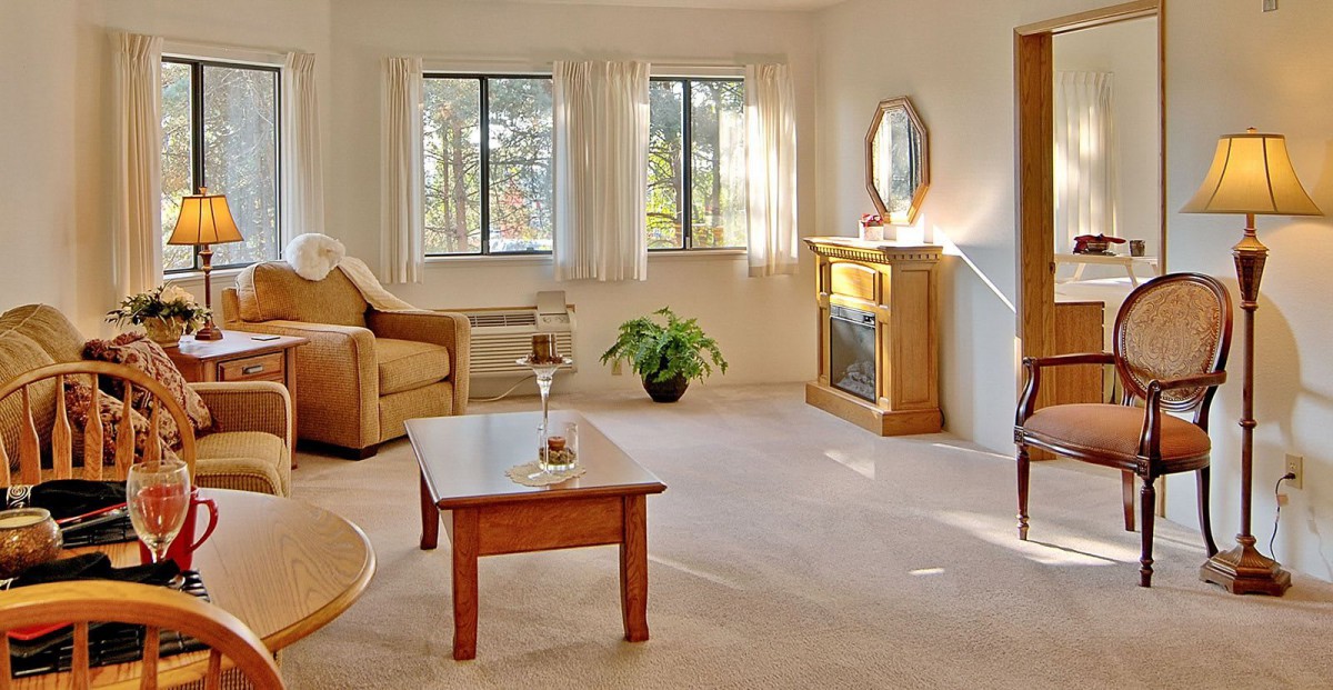 A cozy living room with a sofa, coffee table, and a fireplace, illuminated by natural light from the windows.
