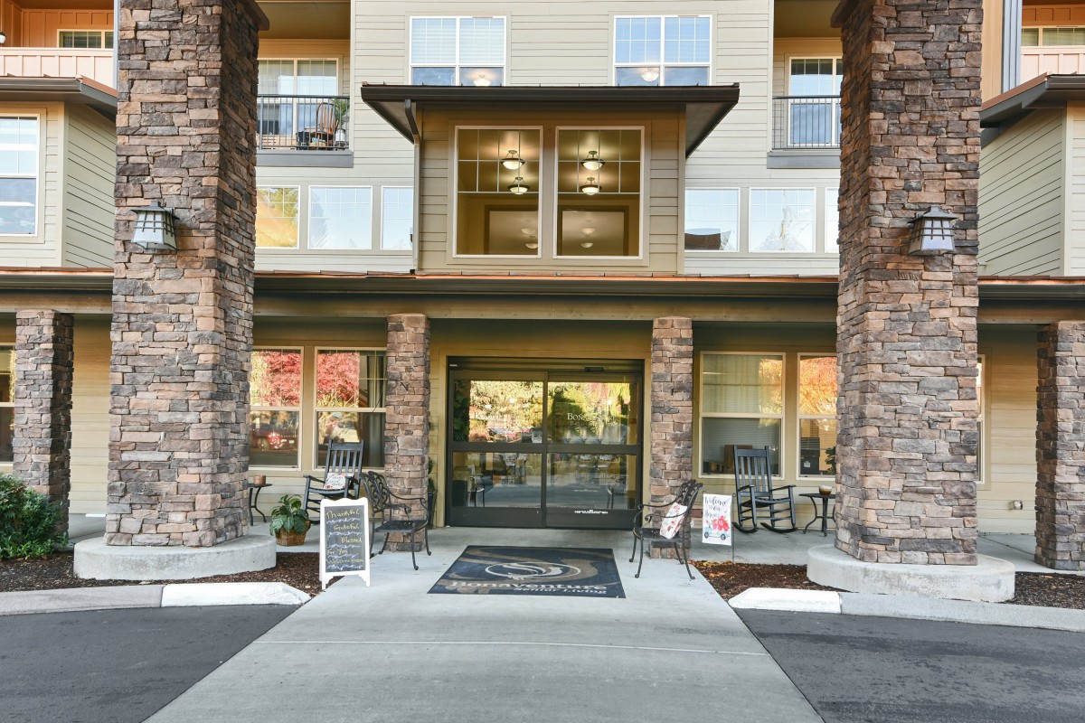 The entrance of a modern building featuring stone columns and large glass doors.