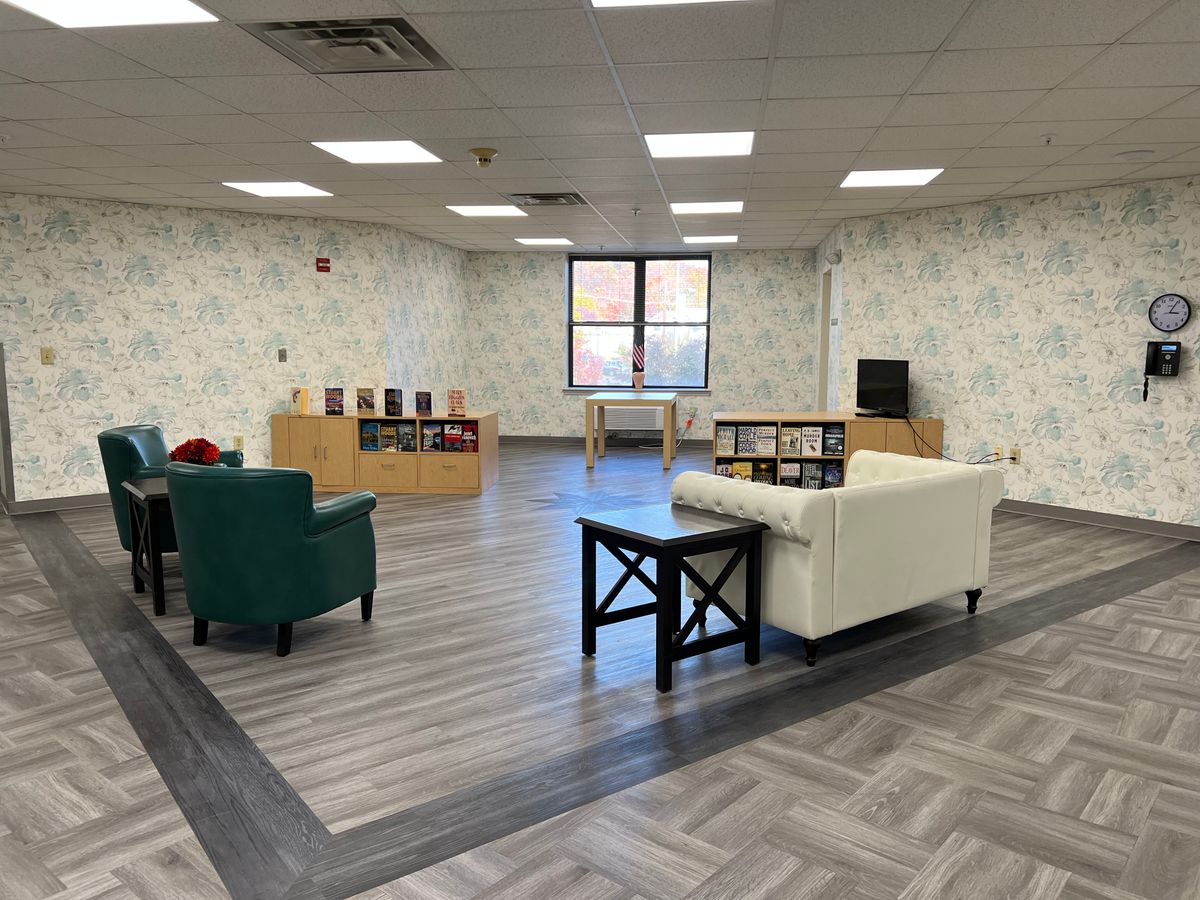 A modern lounge area with comfortable seating, bookshelves, and ample natural light.