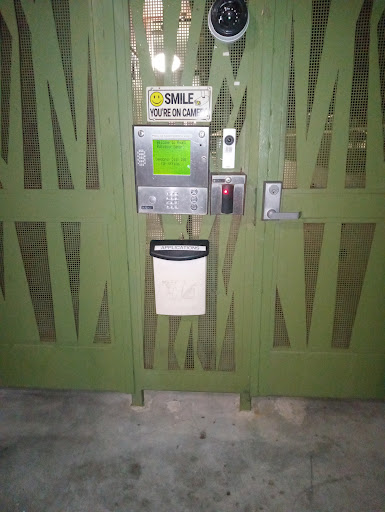 A green security gate with an intercom and a mail slot.